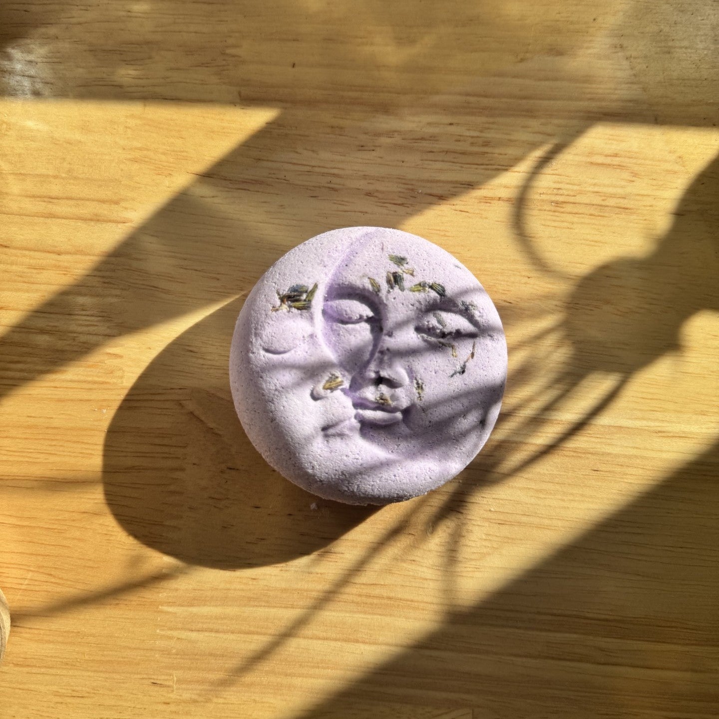 Purple bath bomb with floral elements on a wooden surface